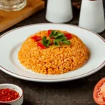 Bulgur Pilavı Kaç Kalori – Bir porsiyon bulgur pilavı, yoğurt ve sebze garnitürleriyle birlikte tabakta sunulmuş.